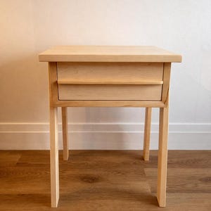 Pu&ograve; includere: Un tavolino in legno chiaro con due cassetti. Il tavolo ha un piano rettangolare e quattro gambe dritte. I cassetti sono a filo con il telaio. Il tavolo &egrave; realizzato in legno chiaro ed &egrave; alto circa 71 cm.