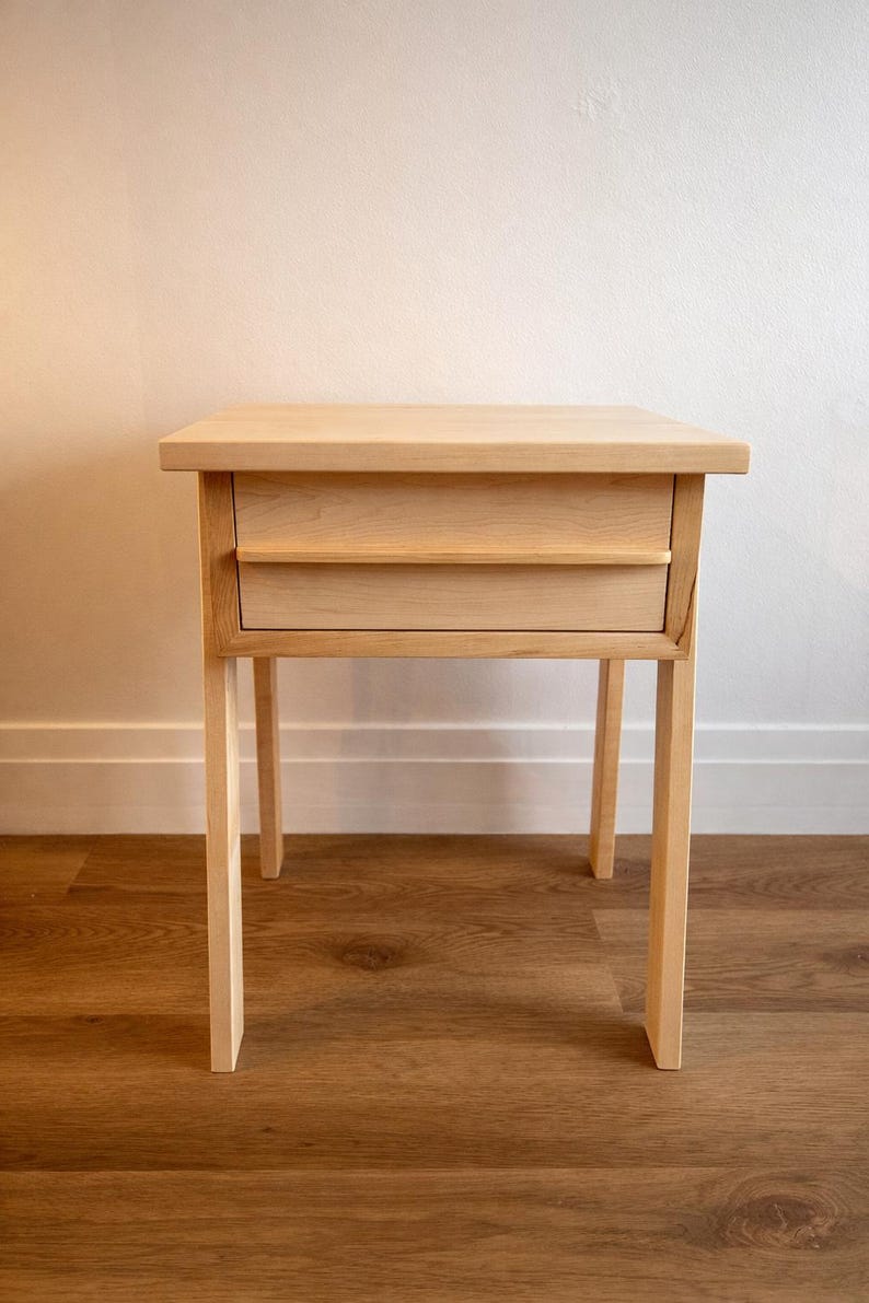 Pu&ograve; includere: Un tavolino in legno chiaro con due cassetti. Il tavolo ha un piano rettangolare e quattro gambe dritte. I cassetti sono a filo con il telaio. Il tavolo &egrave; realizzato in legno chiaro ed &egrave; alto circa 71 cm.