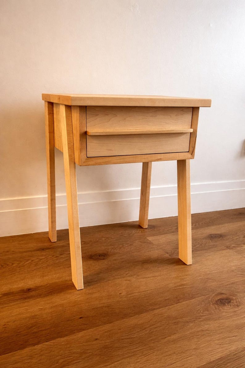 Pu&ograve; includere: Un comodino in legno chiaro con due cassetti e quattro gambe angolate. Il comodino &egrave; realizzato in legno chiaro e ha un design semplice e moderno. I cassetti hanno un piccolo bordo per una facile apertura. Il comodino &egrave; alto 61 cm.