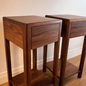Puede incluir: Dos mesitas de noche de madera a juego con un acabado marr&oacute;n oscuro intenso. Cada mesita de noche tiene un solo caj&oacute;n y un estante inferior. El dise&ntilde;o es minimalista y moderno, con l&iacute;neas limpias y una est&eacute;tica c&aacute;lida y natural.