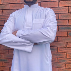 May include: A white long-sleeved shirt with a stand-up collar and a single pocket on the left chest.