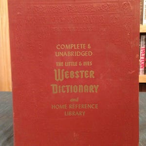 May include: A red hardcover book titled "COMPLETE & UNABRIDGED THE LITTLE & IVES WEBSTER DICTIONARY and HOME REFERENCE LIBRARY." The book has gold lettering and decorative embossed patterns around the edges.