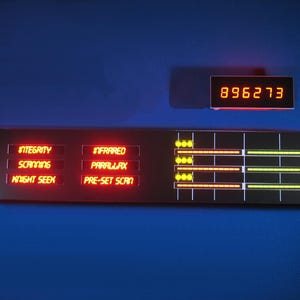 May include: A futuristic control panel with red and yellow illuminated text and displays. The panel includes the words "INTEGRITY", "SCANNING", "KNIGHT SEEK", "INFRARED", "PARALLAX", and "PRE-SET SCAN". A digital display shows the number 896273.