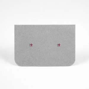 Könnte beinhalten: Ein Paar kleine Ohrstecker mit jeweils einem einzelnen rosafarbenen Edelstein.