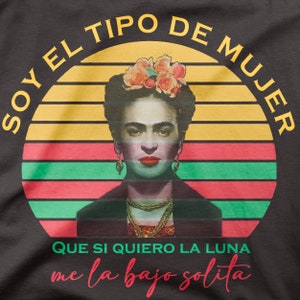 Puede incluir: Una camiseta negra con un gr&aacute;fico de puesta de sol retro que presenta un retrato de Frida Kahlo. El texto "Soy el tipo de mujer que si quiero la luna me la bajo solita" est&aacute; impreso en la camiseta.
