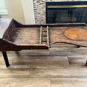 May include: A vintage wooden bench with a built-in drawer and a leather-covered seat. The bench has a distressed finish and is supported by four legs.