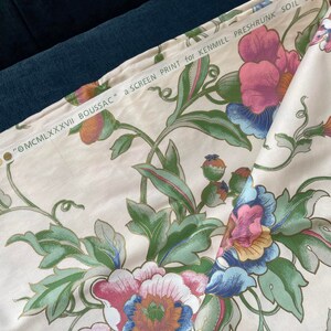 May include: Cream-colored fabric with a large floral pattern in pink, blue, and green. The fabric has a screen print with the text "&copy;MCMLXXXVII BOUSSAC" and "a SCREEN PRINT for KENMILL PRESHRUNK SOIL and S".