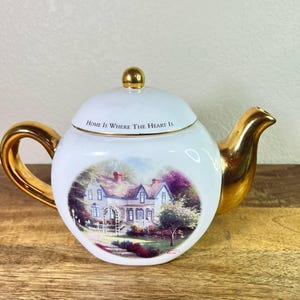 Vintage Thomas Kinkade Tekanna. Home is Where the Heart Is II Tekanna med husbild på båda sidor. Guldfärgad handtag, pip och knopp. Teleflora.
