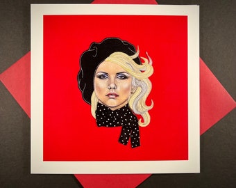 May include: A black and white illustration of a woman with blonde hair wearing a black beret and a black and white polka dot scarf. The illustration is on a red background.