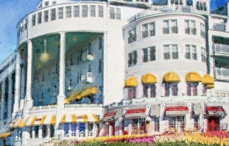May include: A white building with yellow awnings and a large porch. The building has many windows and a balcony. The building is surrounded by flowers.