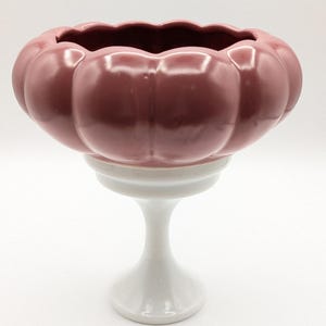 Op de afbeelding: Een roze keramische kom met een gegolfde rand en een witte voet. De kom heeft een pompoenvorm met afgeronde zijden.