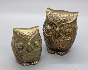 May include: Two brass owl figurines, one larger than the other, with detailed features and a gold finish.