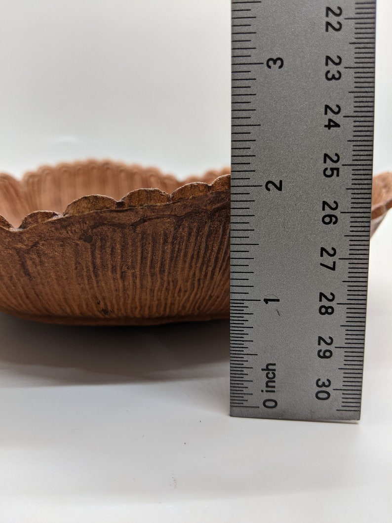 Puede incluir: Un cuenco de cer&aacute;mica marr&oacute;n con un borde festoneado, que mide aproximadamente 18 cm de di&aacute;metro. El cuenco est&aacute; sobre una superficie blanca junto a una regla.