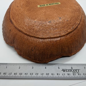 Puede incluir: Un plato de cer&aacute;mica marr&oacute;n con un borde texturizado. El plato tiene un di&aacute;metro de aproximadamente 15 cm y tiene una etiqueta que dice "MADE IN MONTANA".