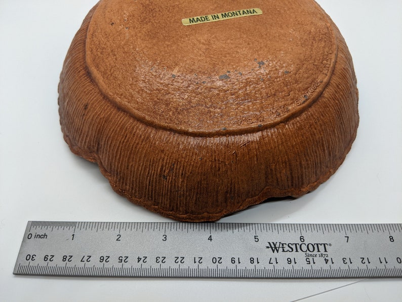 Puede incluir: Un plato de cer&aacute;mica marr&oacute;n con un borde texturizado. El plato tiene un di&aacute;metro de aproximadamente 15 cm y tiene una etiqueta que dice "MADE IN MONTANA".