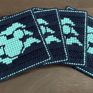 Peut inclure: Ensemble de cinq sous-verres bleus et turquoise avec un motif géométrique. Les sous-verres sont en tissu et ont une bordure cousue.