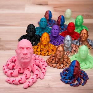 May include: A collection of colorful, 3D-printed octopus figures, each featuring a human face. The figures are in various colors, including pink, black, blue, purple, and gold. The octopus tentacles are articulated.