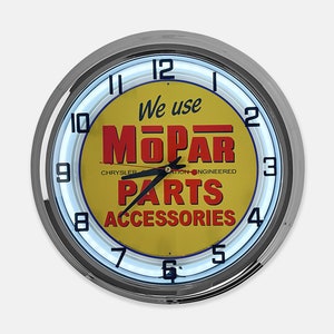May include: Round wall clock with a chrome finish and a yellow face. The clock face features the text "We use MOPAR PARTS ACCESSORIES" in red and white lettering. The clock has a blue neon light around the face.