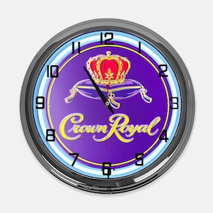 May include: Round wall clock with a black frame, featuring a purple background with the Crown Royal logo. The logo includes a red crown on a purple pillow, with the words "Crown Royal" in yellow script. The clock has black hands and white numerals.