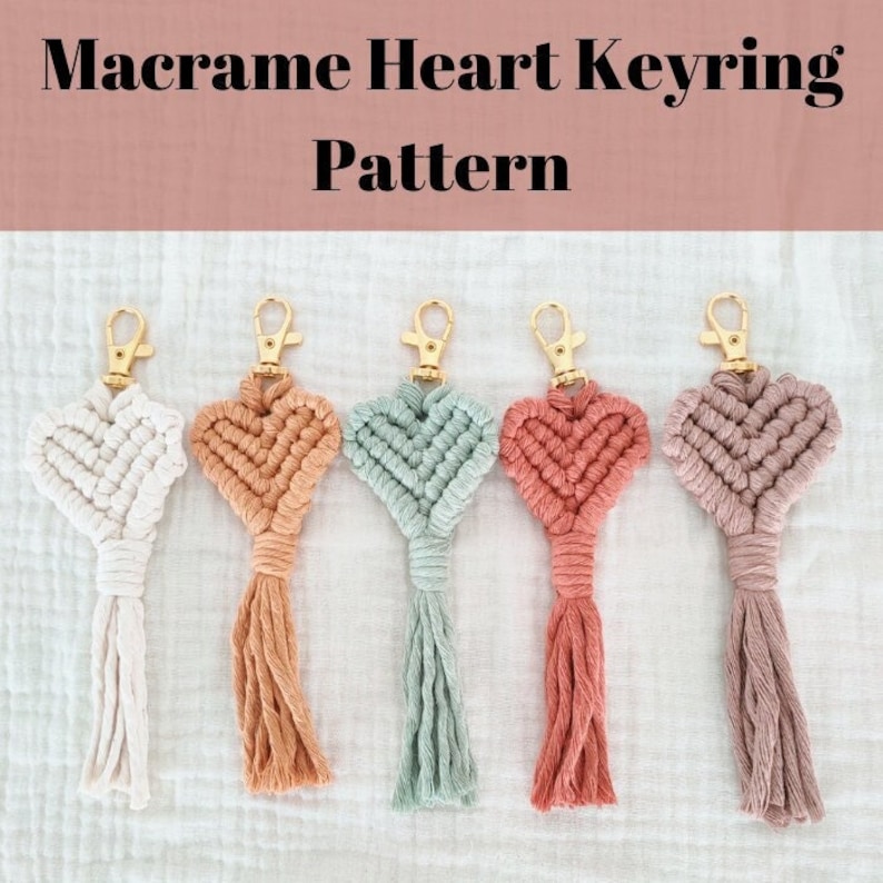 Pode incluir: Cinco chaveiros de cora&ccedil;&atilde;o em macram&eacute; em v&aacute;rias cores: branco, p&ecirc;ssego, verde menta, coral e malva. Cada chaveiro apresenta um fecho dourado e uma borla. O texto "Macrame Heart Keyring Pattern" est&aacute; vis&iacute;vel no topo.