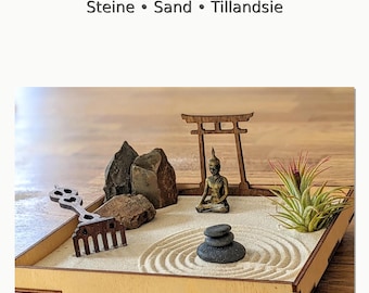 May include: A miniature Zen garden set in a wooden tray. The set includes a small Buddha statue, rocks, sand, a rake, and a small plant. The text "Zen-Garten Set" is at the top of the image.