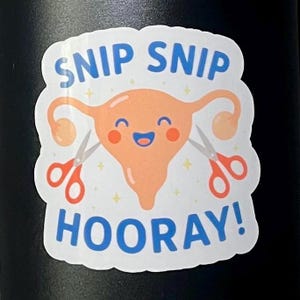 May include: A white sticker with a cartoon uterus design. The uterus is peach-colored with a smiling face and is being cut by two pairs of scissors. The words "SNIP SNIP HOORAY!" are written in blue.