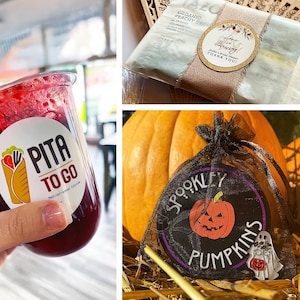 Op de afbeelding: Een doorzichtige plastic beker gevuld met een rode drank, met een wit etiket met de tekst "Pita To Go". Een theepakket met een decoratief etiket en een zwarte mesh tas met een "Spookley Pumpkins" patch zijn ook afgebeeld.