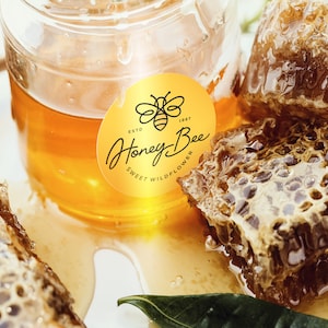 May include: A gold sticker with the text "Honey Bee" and "Sweet Wildflower" on a jar of honey with honeycomb.