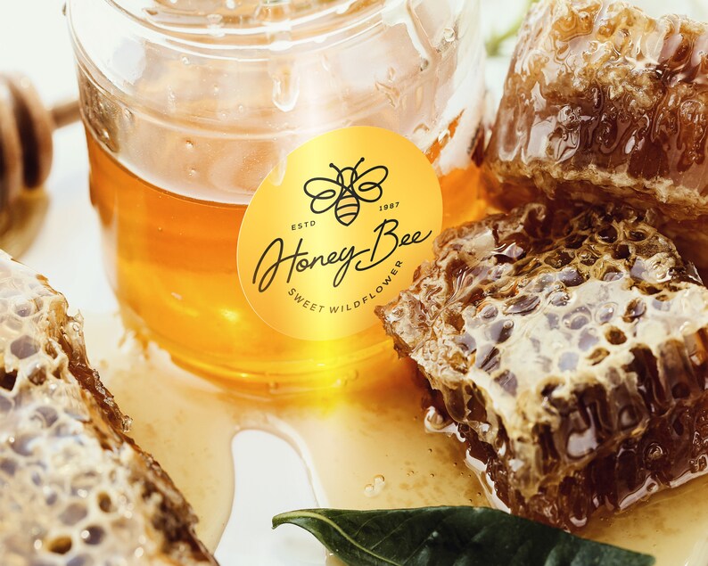 May include: A gold sticker with the text "Honey Bee" and "Sweet Wildflower" on a jar of honey with honeycomb.
