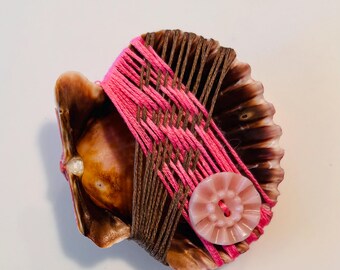 In zen-stijl gewikkelde schelp, meditatieve decoratie waarbij roze de binnenkant van de schelp weerspiegelt; zie beschrijving:
