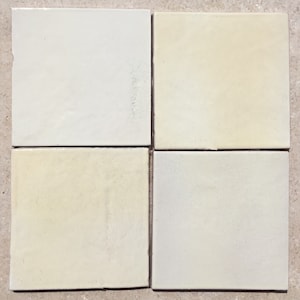 May include: Four square ceramic tiles in various shades of white and cream. The tiles are arranged in a 2x2 grid.