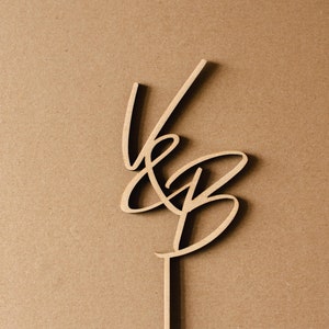 Könnte beinhalten: Holz-Kuchentopper mit den Buchstaben "V & B" in einem kursiv geschriebenen Stil.