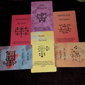 Puede incluir: Un conjunto de cinco cartas de or&aacute;culo rectangulares dispuestas en forma de cruz. Las cartas presentan fondos coloridos, sellos negros y texto que incluye nombres como Andromalius, Orias, Marchosias, Buer, Orobas y Beleth con sus t&iacute;tulos.