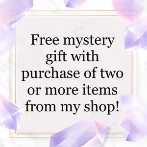 May include: A white background with a gold frame around a text box that says "Free mystery gift with purchase of two or more items from my shop!" The background is decorated with purple and pink crystal shapes.