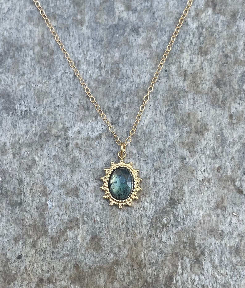 May include: A gold chain necklace with a green gemstone pendant set in a gold filigree frame.
