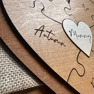 Puede incluir: Rompecabezas de madera en forma de coraz&oacute;n con acabado marr&oacute;n claro. Las piezas del rompecabezas est&aacute;n grabadas con nombres y la palabra "Mummy" en una pieza en forma de coraz&oacute;n. Un regalo personalizado.