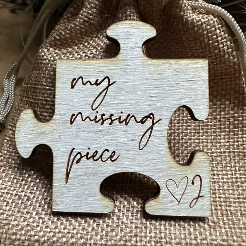 May include: A wooden puzzle piece with the words "my missing piece" and a heart symbol. The piece is light brown and has a rough texture.