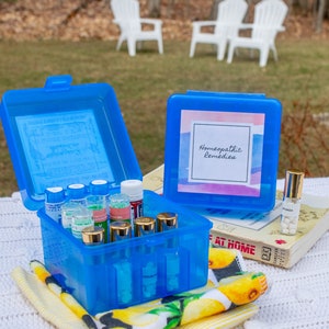 May include: A blue plastic box with a label that says "Homeopathic Remedies" and is filled with small glass bottles. The box is sitting on a white crocheted blanket with a yellow and white patterned towel.