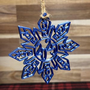 May include: A blue snowflake-shaped Christmas ornament with the year 2025 printed on it.