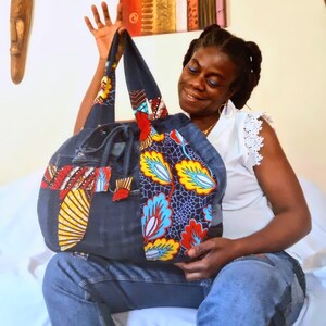Peut inclure: Un grand sac cabas en jean bleu avec des panneaux de tissu colorés. Le sac a un design patchwork avec des motifs floraux rouges, jaunes et bleus. Le sac est fabriqué à partir de denim recyclé et présente un design unique et fait main.