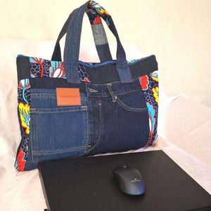 May include: A blue denim tote bag with a colorful fabric lining and a label that says "OBAMS BAGS". The bag is sitting on a white surface with a black laptop and a black computer mouse.