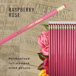 May include: A pack of 12 personalised pink wooden pencils with gold foil lettering that reads "JADWIGA'S LUCKY PENCIL". The pencils are displayed against a vintage floral background with the text "RASPBERRY ROSE".