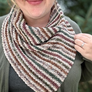 May include: A crocheted infinity scarf with a striped pattern in shades of brown, green, white, and pink.