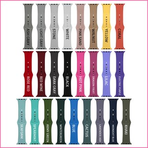 May include: A set of 20 different colored Apple Watch bands. The bands are made of silicone and come in a variety of colors, including red, blue, green, black, white, and pink. The bands are all shown in a row, with the color name printed on each band.