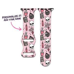 May include: Pink watch strap featuring a repeating pattern of skulls, potion bottles, candles, planchette, and books. The text "ASK FOR GUIDANCE" is included. The text "PERSONALIZE IT! ADD YOUR NAME" is also included.