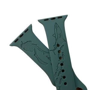 Op de afbeelding: Een tealblauwe Apple Watch band met een duiker- en haai-ontwerp. De band heeft een herhalend patroon van vissen.