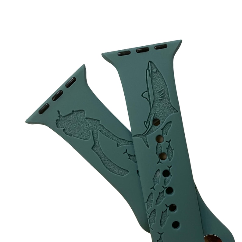 Op de afbeelding: Een tealblauwe Apple Watch band met een duiker- en haai-ontwerp. De band heeft een herhalend patroon van vissen.
