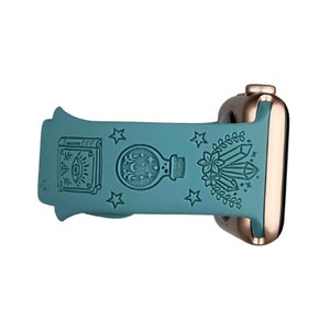 May include: A teal blue silicone watch band with a rose gold watch case. The band features a variety of embossed designs including a book, a potion bottle, crystals, and stars.