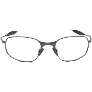 May include: A pair of rimless eyeglasses with a dark gray metal frame. The lenses are clear, and the nose pads are a darker gray. The temples have a curved design and are tipped with black rubber.