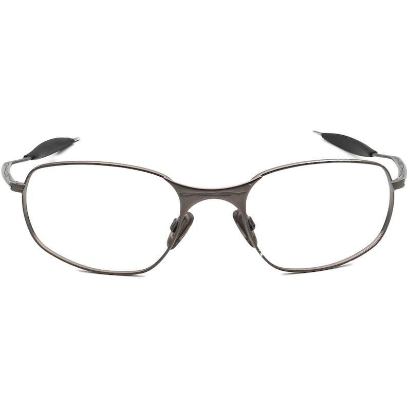 May include: A pair of rimless eyeglasses with a dark gray metal frame. The lenses are clear, and the nose pads are a darker gray. The temples have a curved design and are tipped with black rubber.